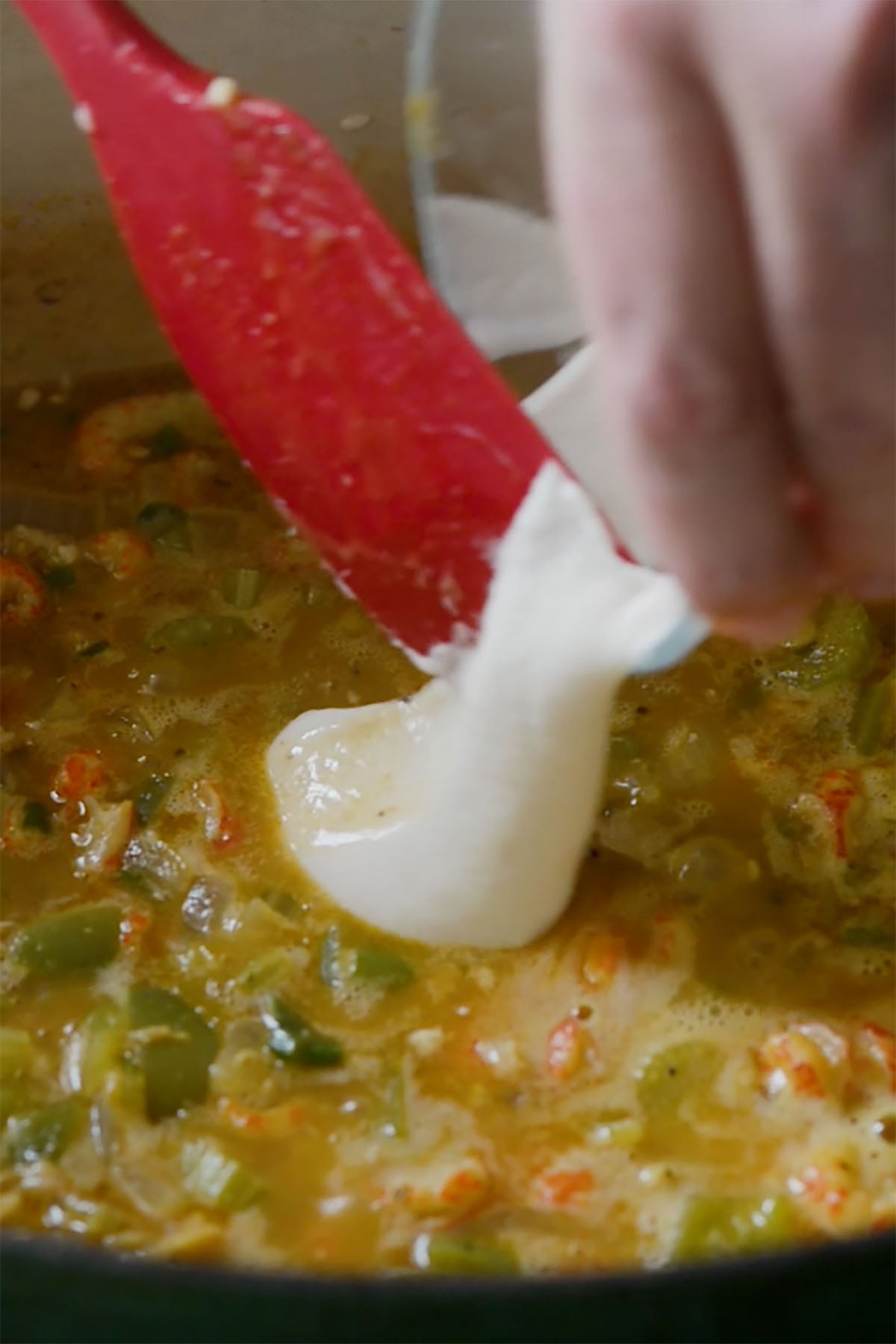 A slurry being poured into crawfish étouffée.
