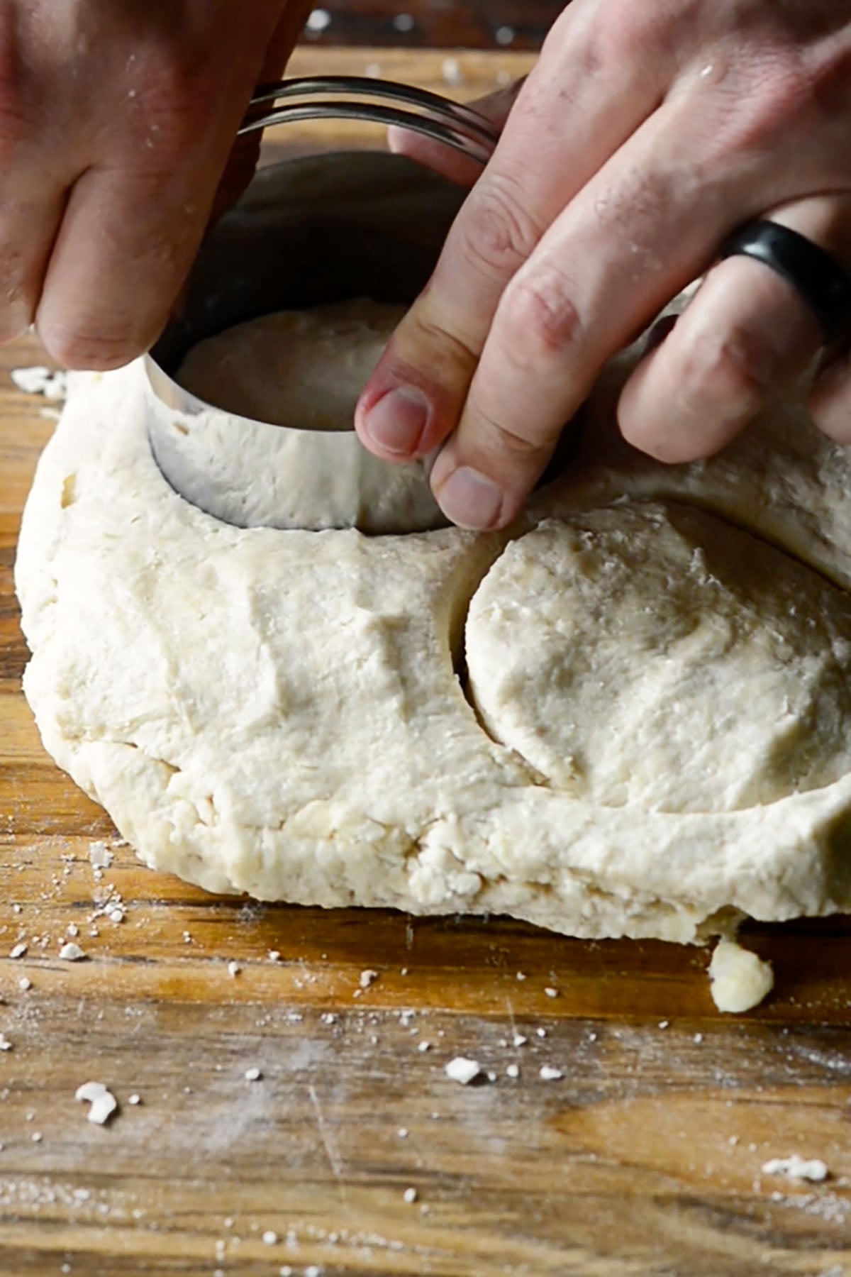 Buttermilk biscuit dough being cut into biscuits using a biscuit cutter.