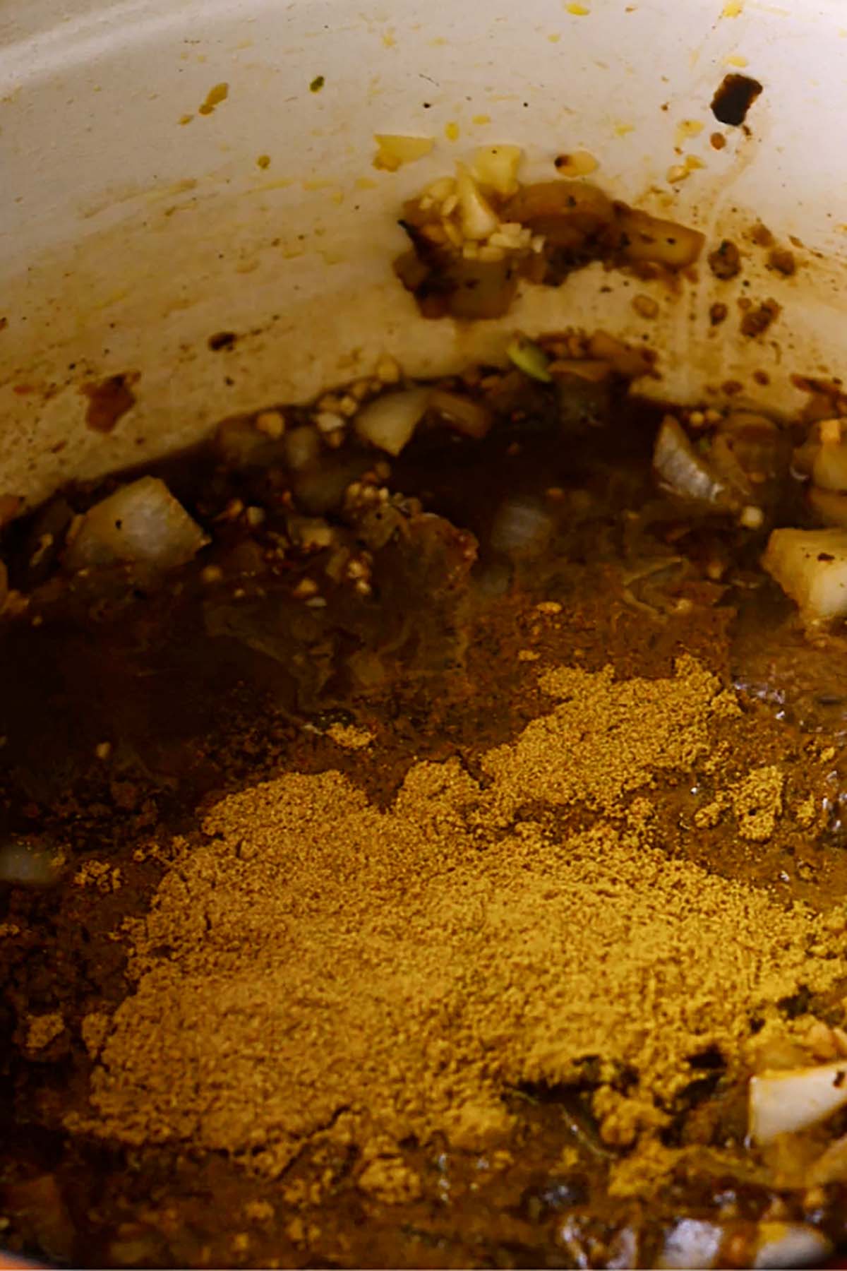 Yellow curry being added to a filipino chicken curry sauce.