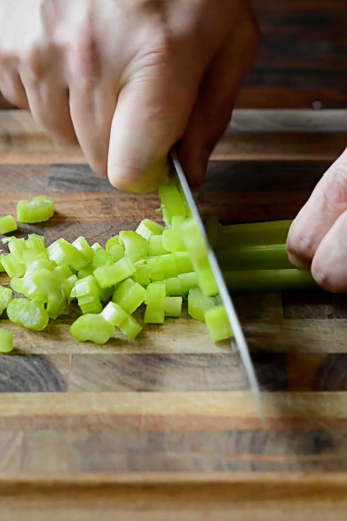 Celery being sliced on a cutting board.