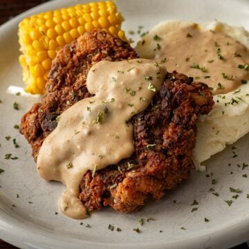 Chicken fried steak and mashed potatoes covered in cream gravy and served with corn on the cob.