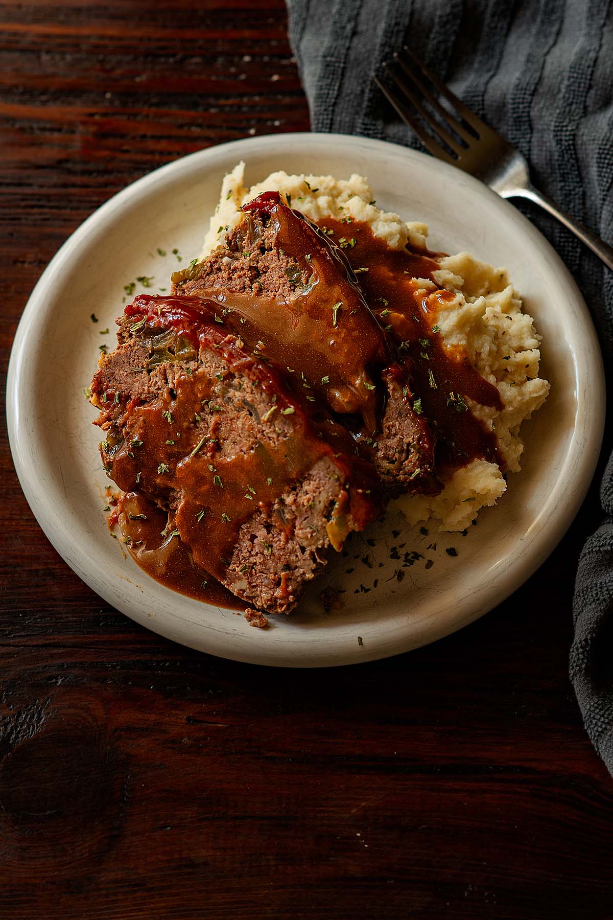 Two slices of meatloaf served over mashed potatoes and topped off with homemade brown gravy.