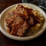 Two slices of classic southern meatloaf with mashed potatoes and brown gravy.