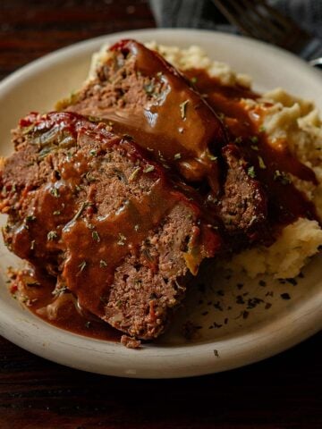 Two slices of classic southern meatloaf with mashed potatoes and brown gravy.