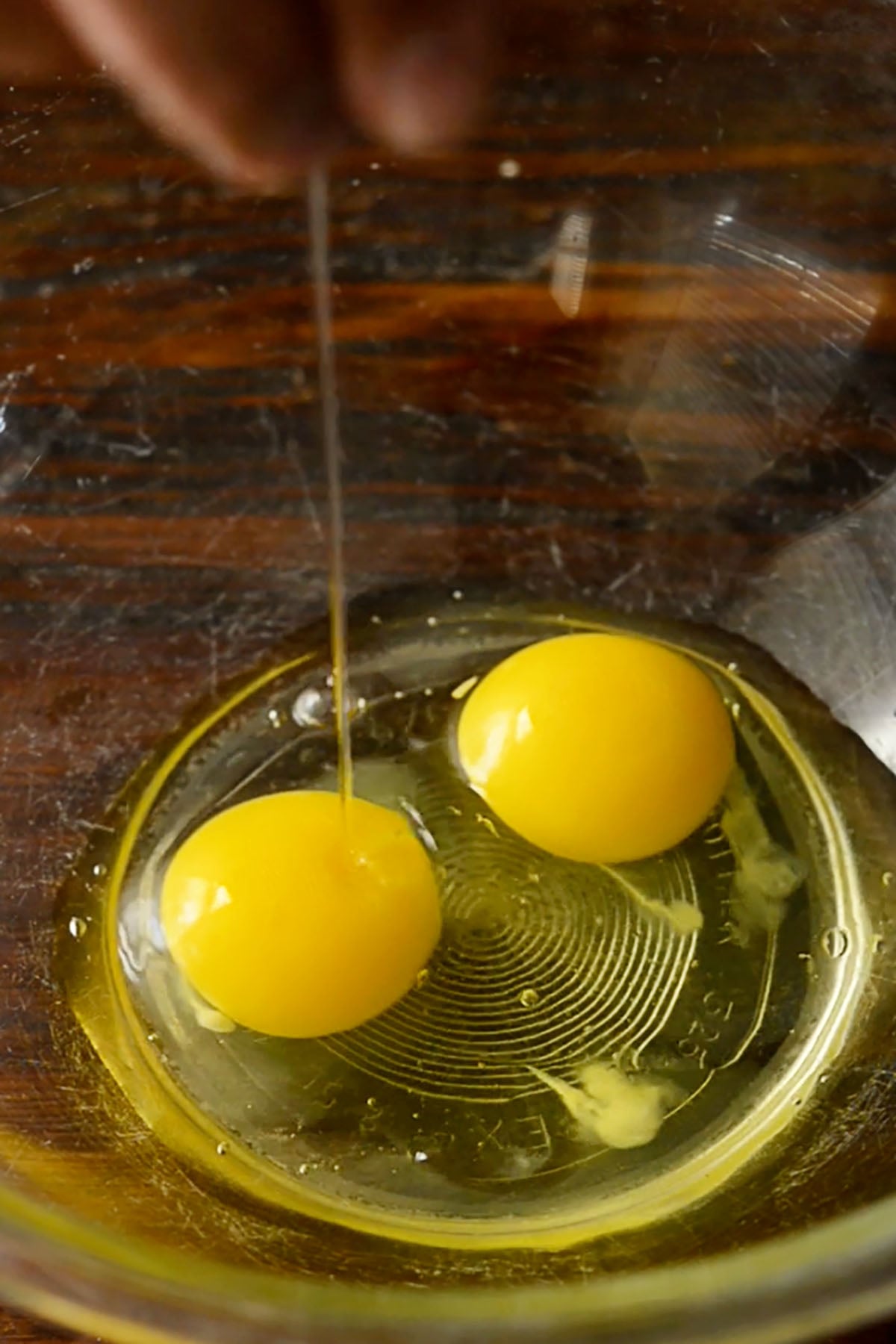 Two eggs cracked in a a mixing bowl.
