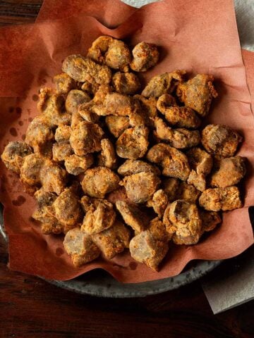 Southern fried chicken gizzards served hot and crispy on a pink butcher lined plate.