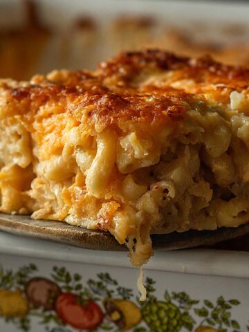 A melty slice of southern baked mac and cheese on a wooden spatula.