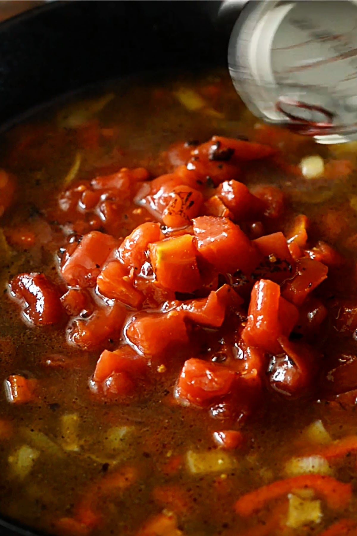 The base of a cajun pasta sauce with fire roasted tomatoes cooking in a cast iron skillet. 