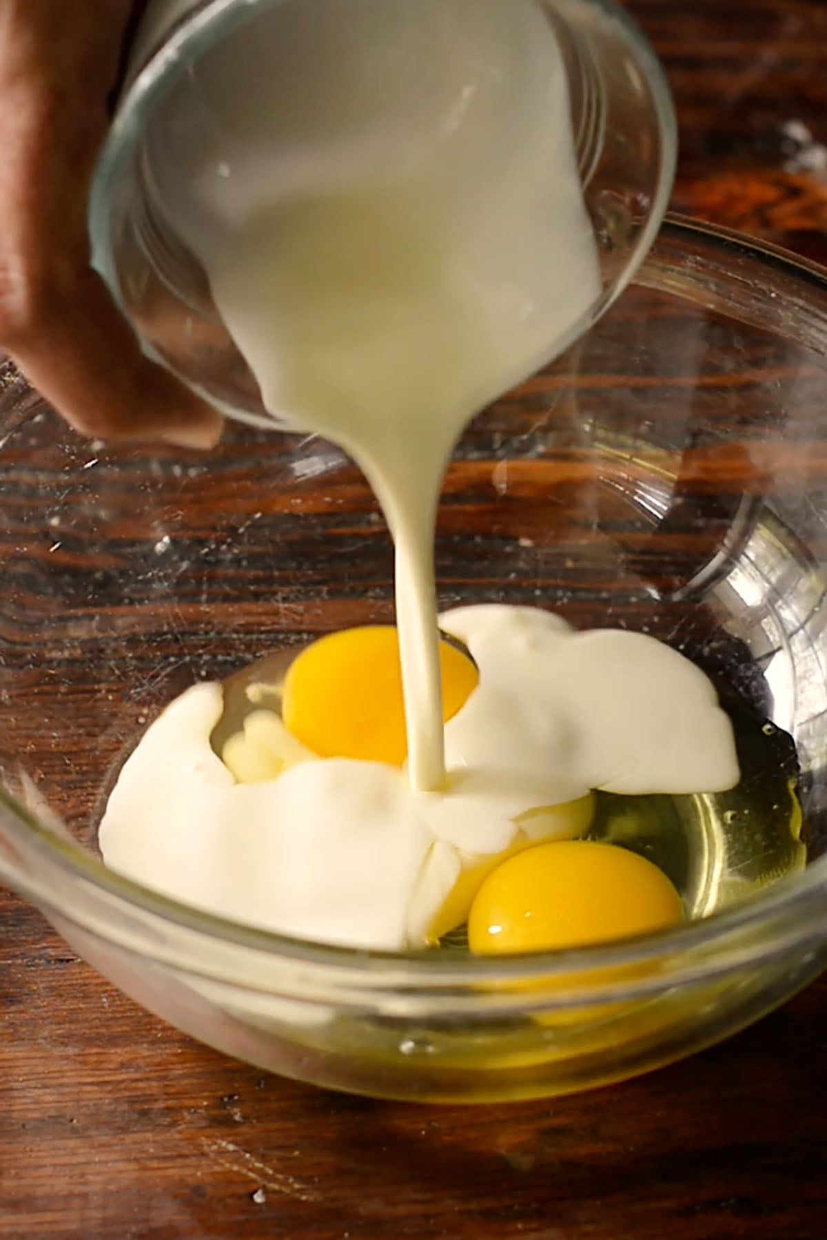 Eggs and heavy cream being mixed together in a glass mixing bowl.