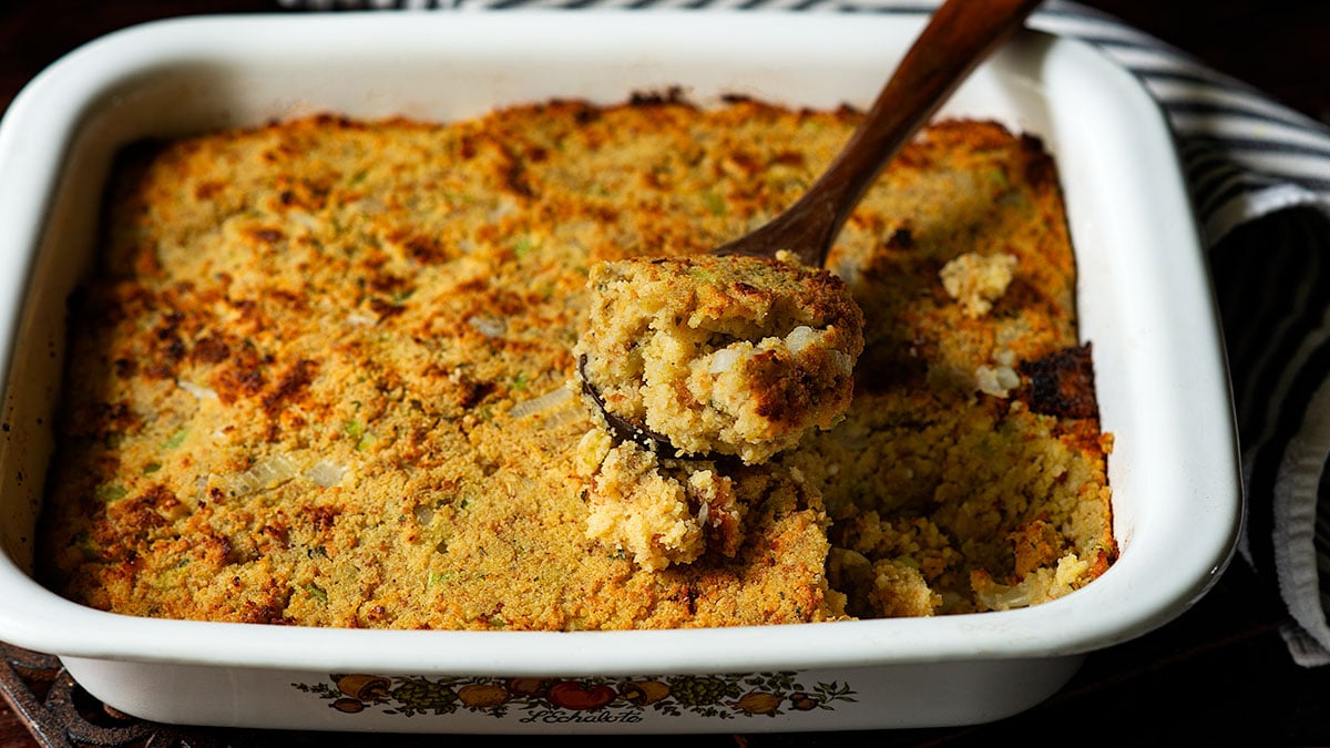Southern Cornbread Dressing being scooped out of a serving dish.