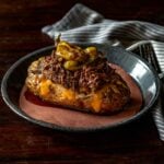 Mississippi served on a baked potato with cheese and topped with two pepperoncini peppers.