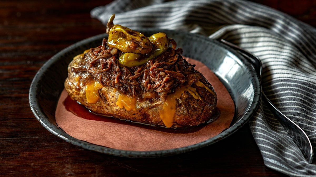 Mississippi pot roast served over a cheesy loaded baked potato.