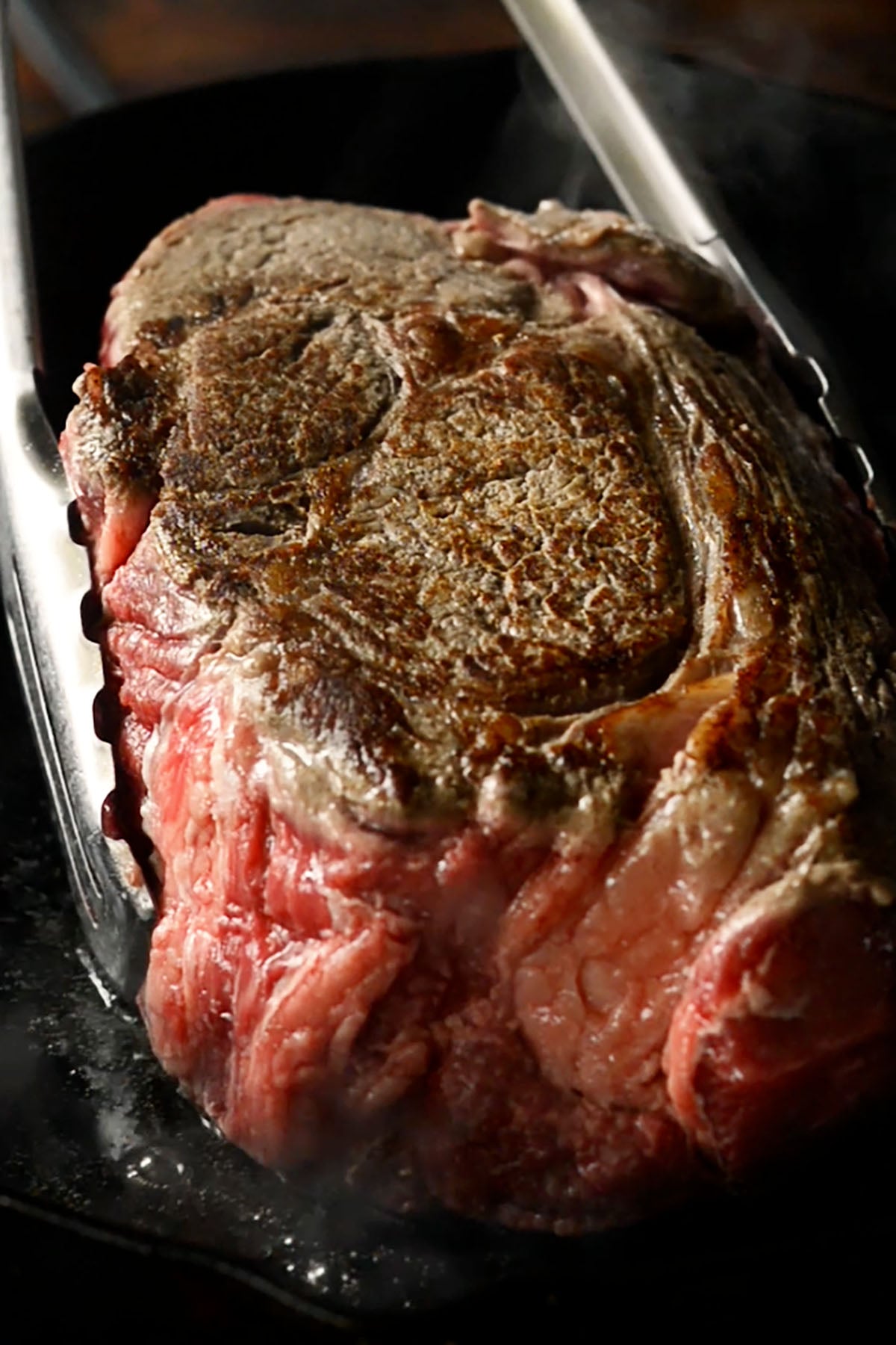 Chuck roast being seared in a cast iron skillet.