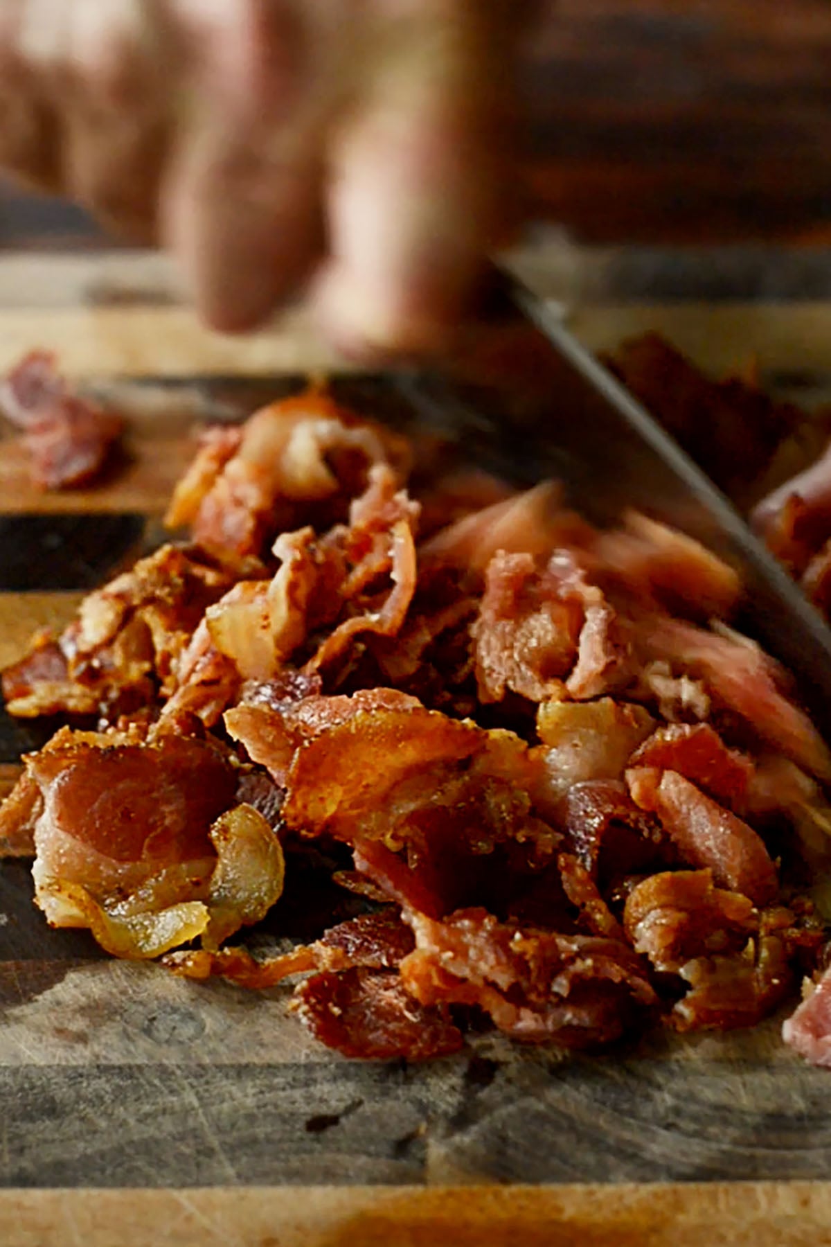 Bacon being chopped on a wooden cutting board for Instant Pot Black Eyed Peas.