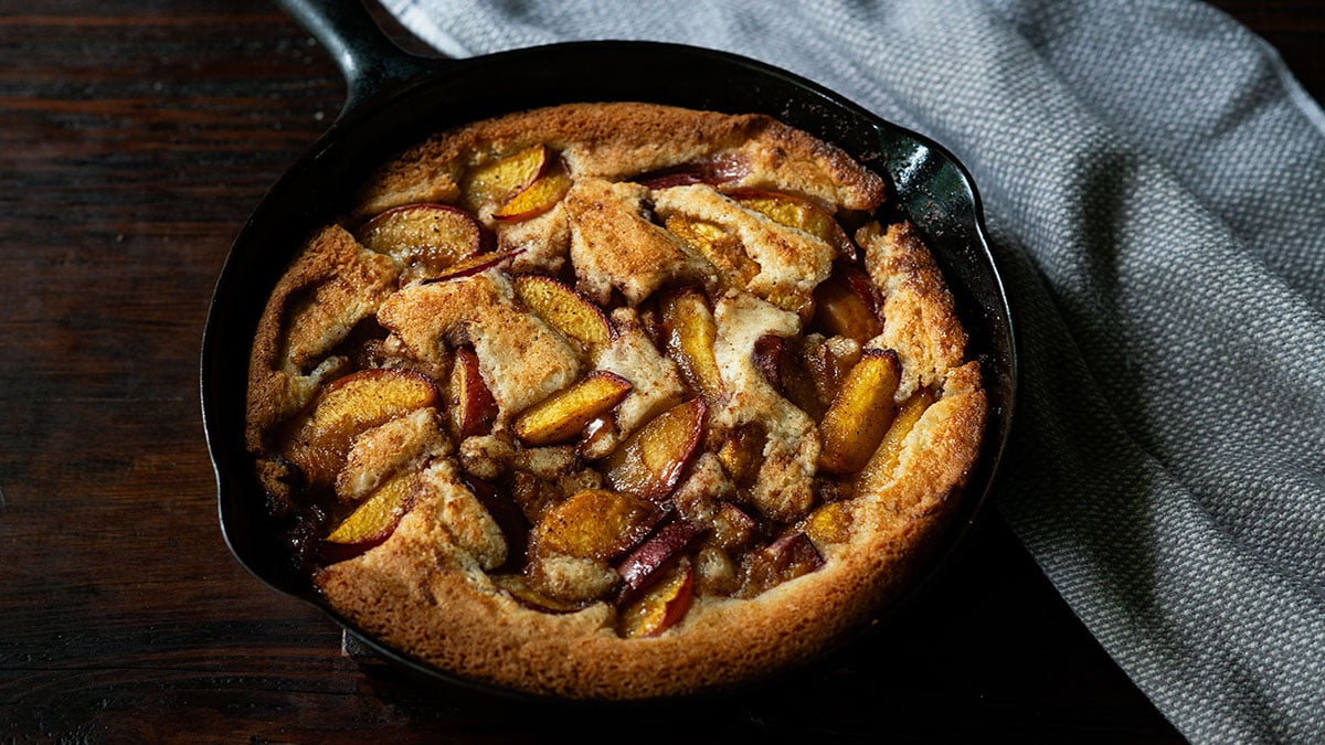 Homemade Southern peach cobbler baked and served in a cast iron skillet.