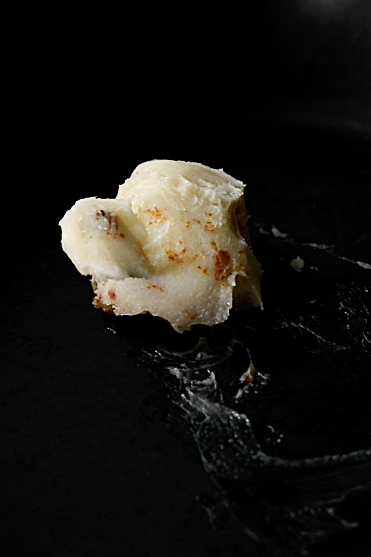 Cold bacon grease melting in a cast iron skillet.