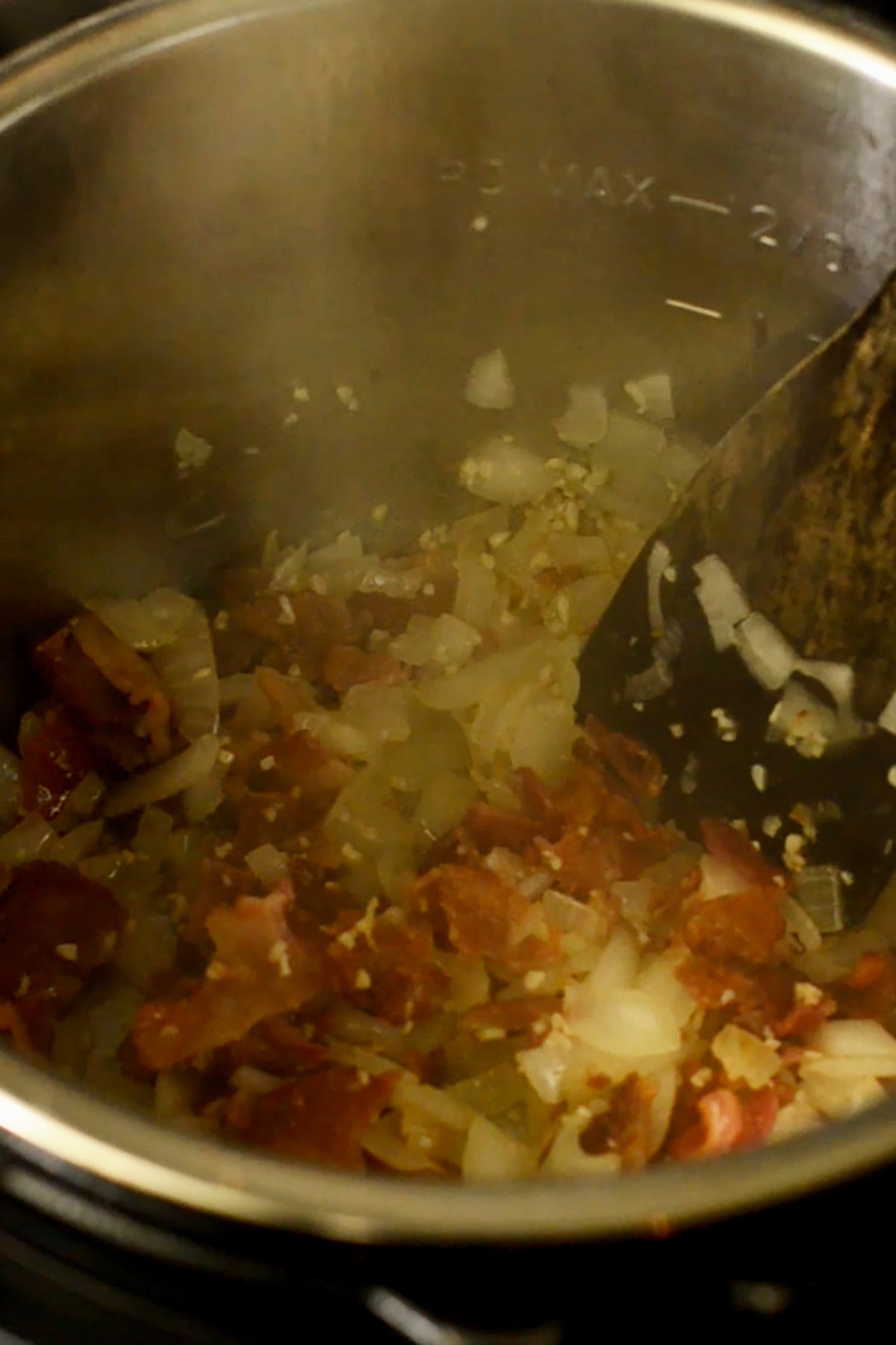 Onions, bacon, and garlic sautéing in an Instant pot for black eyed pea base.