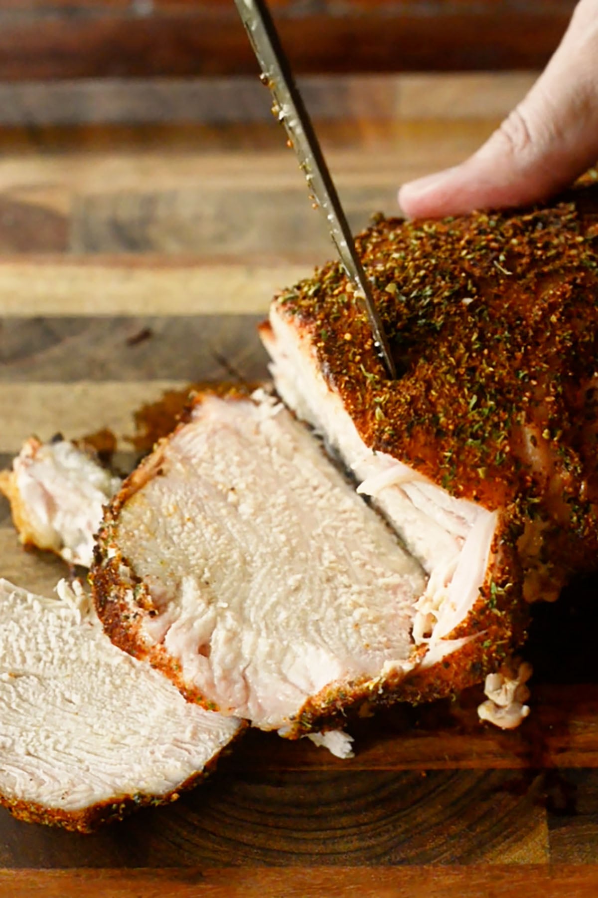 Southern smoked turkey breast being sliced on a wood cutting board.