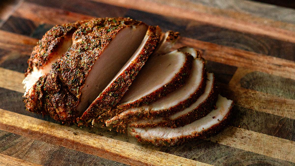 Sliced smoked turkey breast on a wood cutting board.