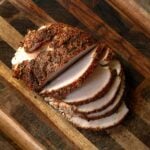Sliced smoked turkey breast on a wooden cutting board.