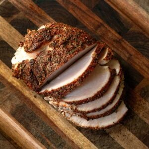 Sliced smoked turkey breast on a wooden cutting board.
