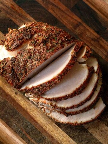 Sliced smoked turkey breast on a wooden cutting board.