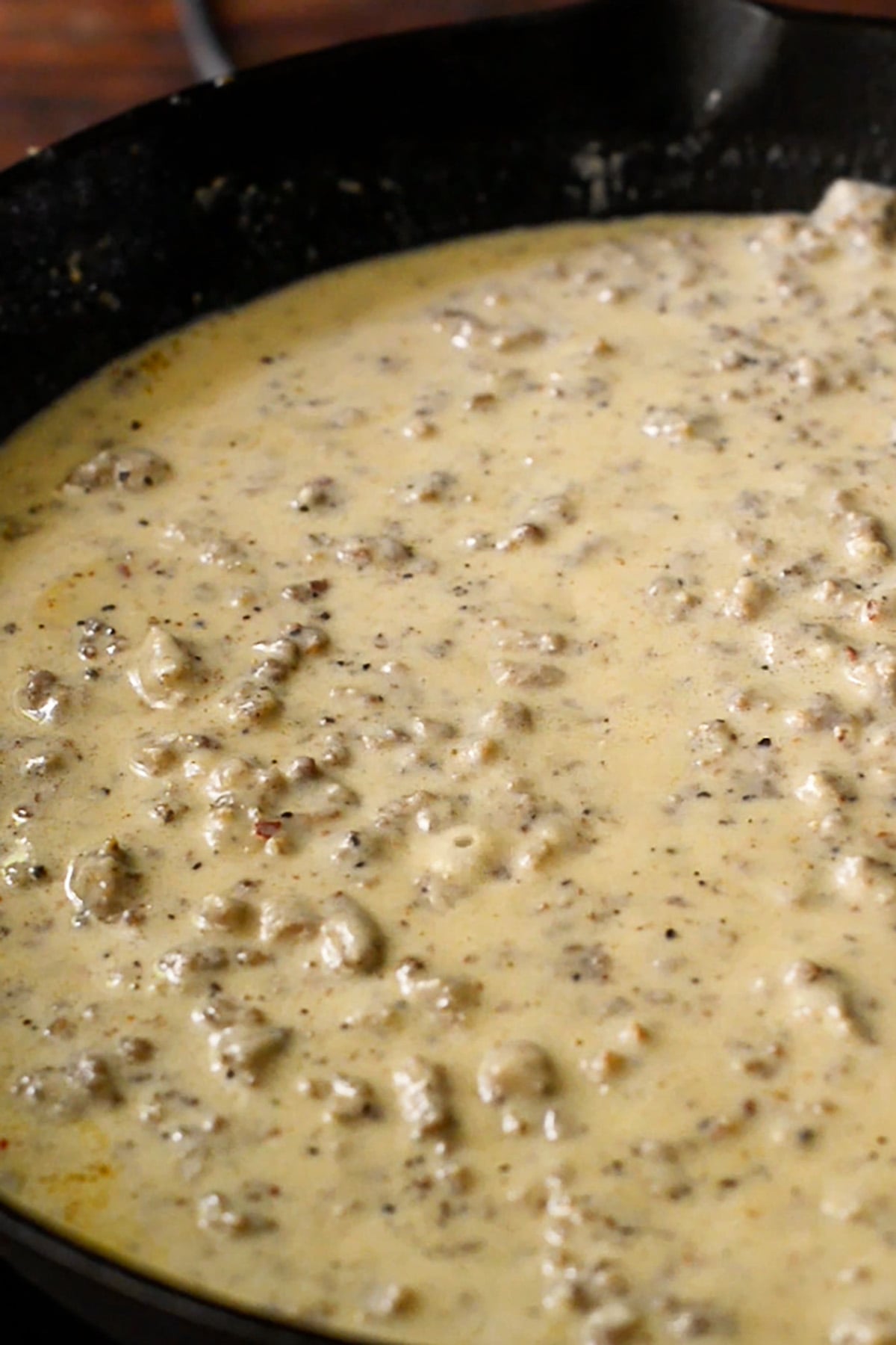 Southern sausage gravy simmering in a cast iron skillet.