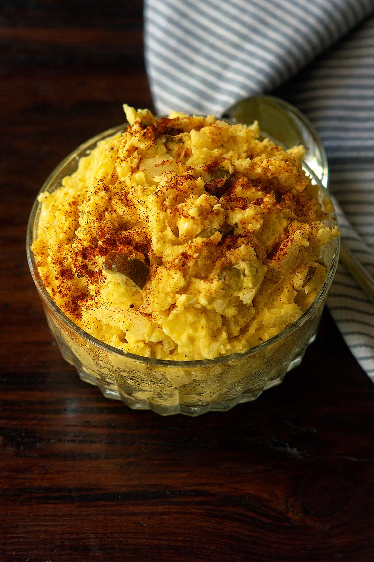 Southern potato salad served in a glass bowl and topped with a sprinkle of paprika.