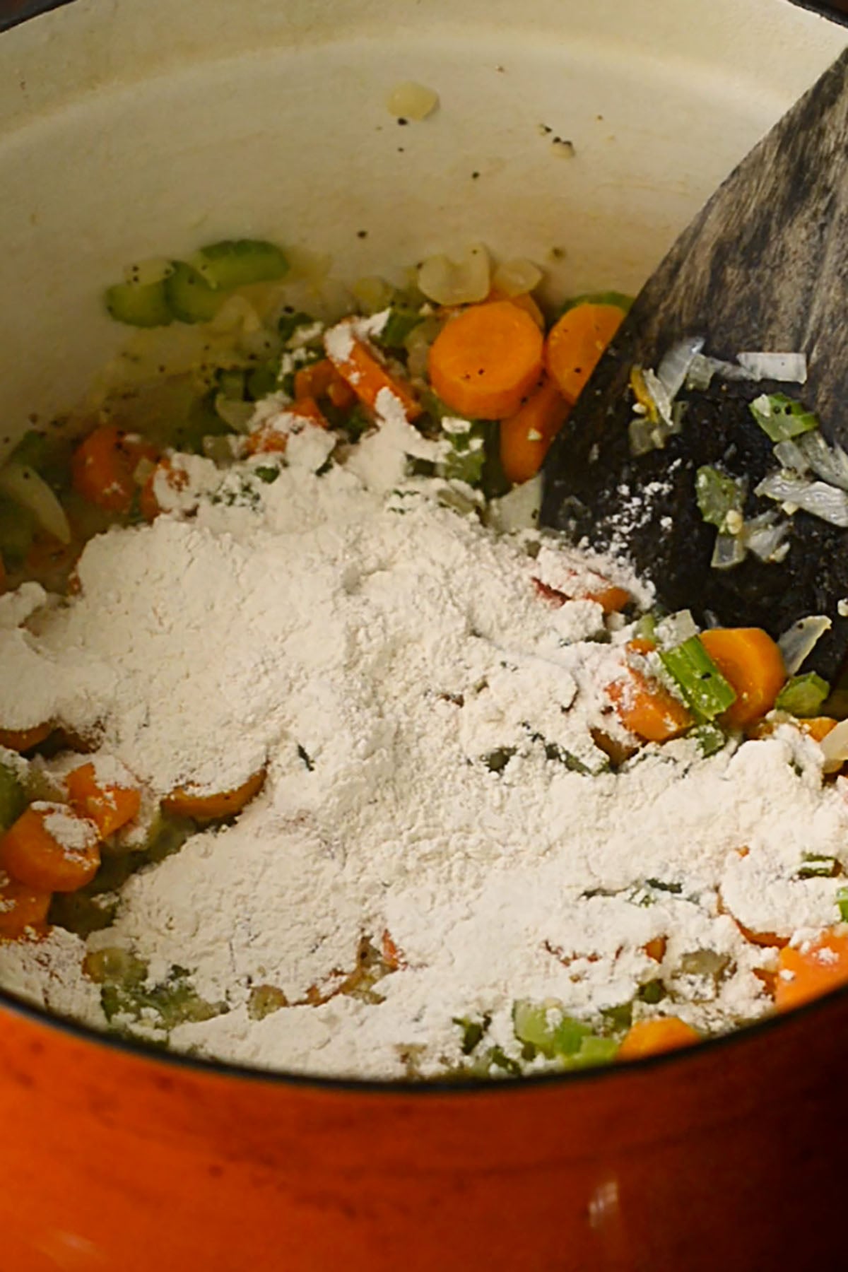 Flour covering sautéed vegetables with melted butter for a chicken and dumpling roux.