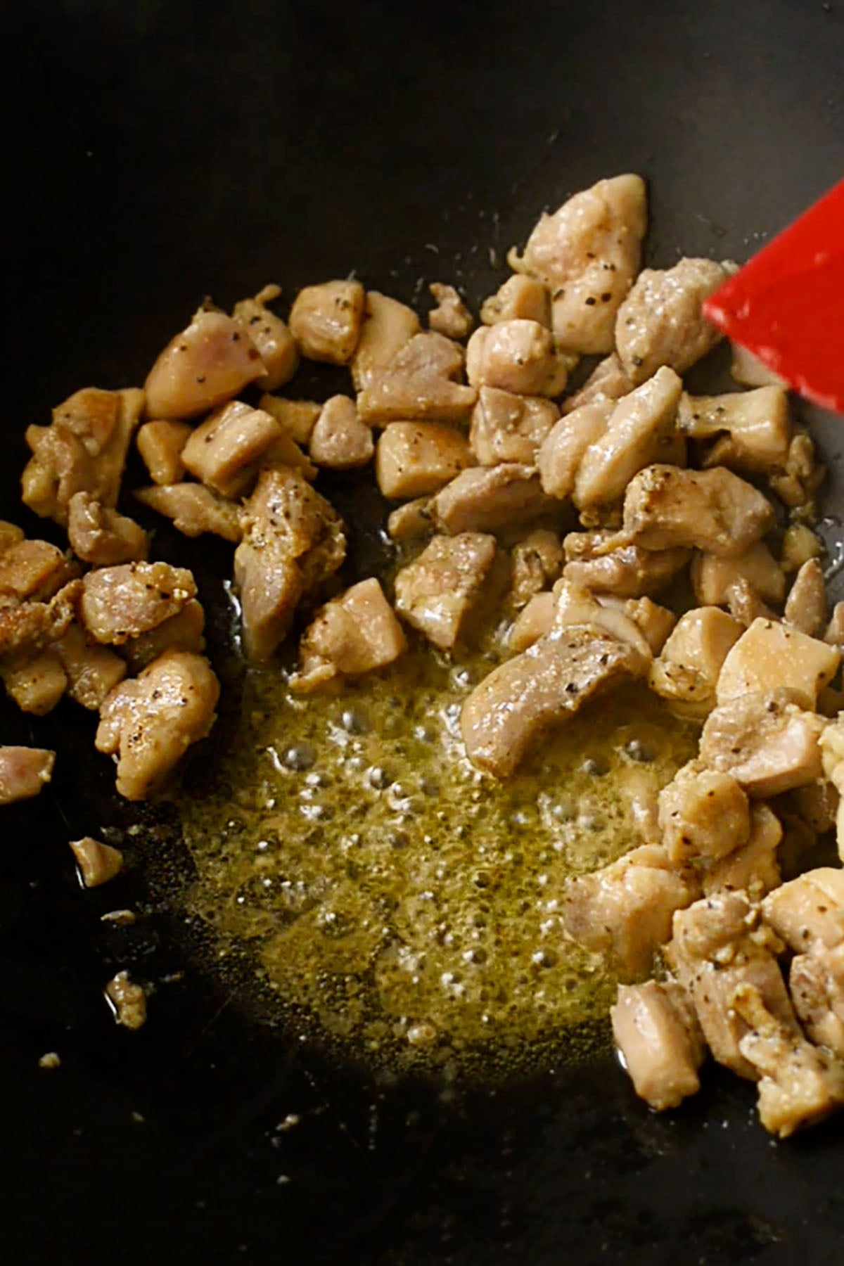 Cubed chicken thighs cooking in a wok.