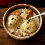 Classic creamy southern chicken and dumplings served in a brown rustic bowl.