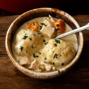 Classic creamy southern chicken and dumplings served in a brown rustic bowl.