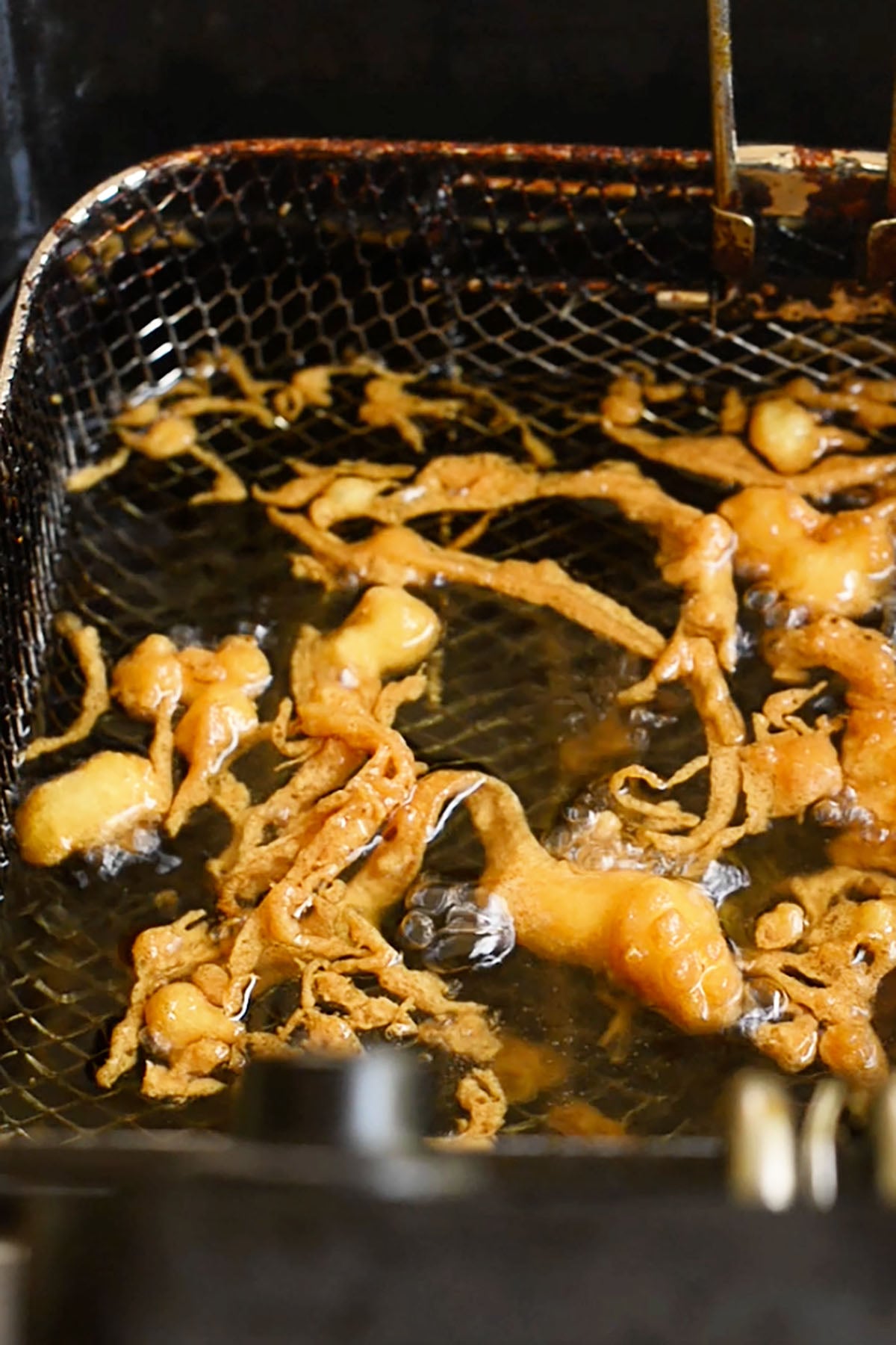 Copycat Long John Silver's crunchies frying in a deep fryer.