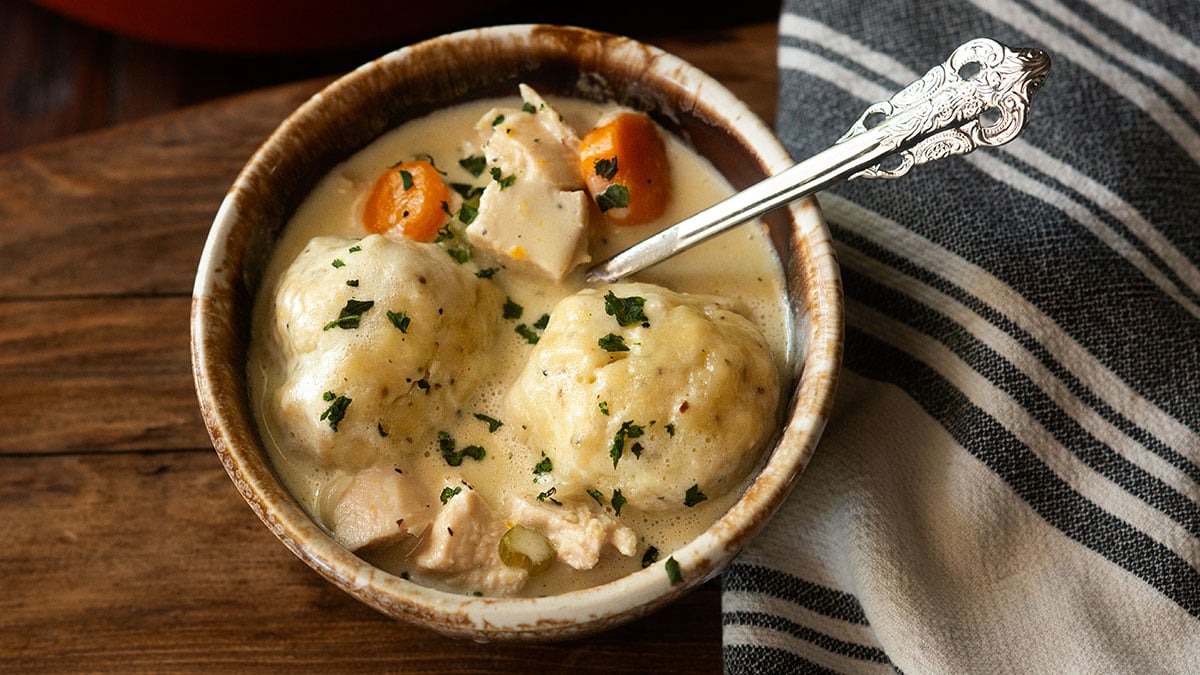 Creamy classic southern chicken and dumplings served in a rustic bowl with a vintage spoon.