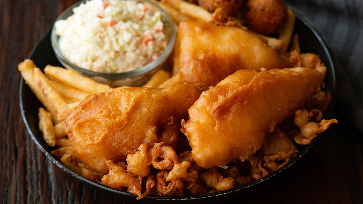 Crispy fried cod with french fries, hush puppies, and coleslaw all served in one platter.
