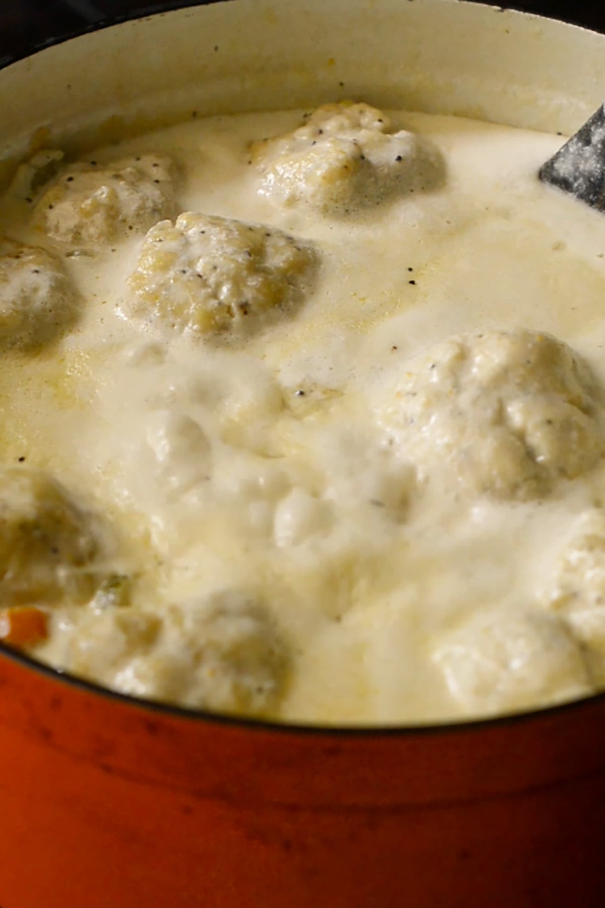 Buttermilk dumplings cooking in a creamy chicken soup.