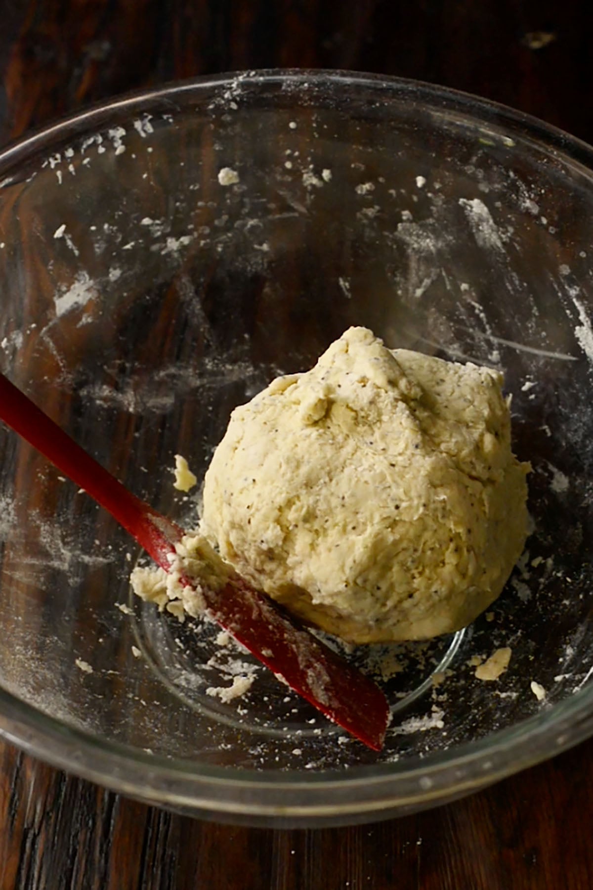 A ball of buttermilk dumpling dough resting in a glass mixing bowl.