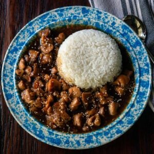 Bourbon chicken served in a vintage blue and white bowl with steamed white rice.