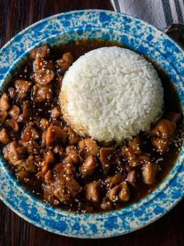 Bourbon chicken served in a vintage blue and white bowl with steamed white rice.