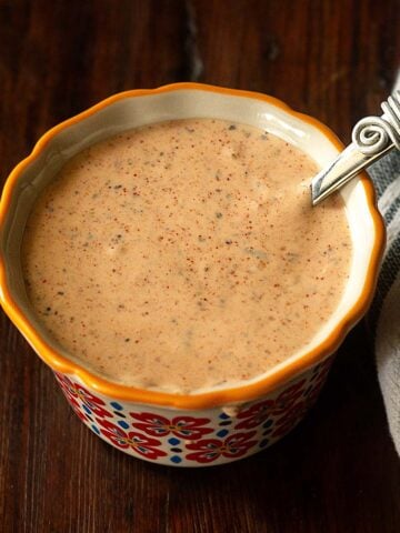 Cajun remoulade served in a ramekin with a small serving spoon.