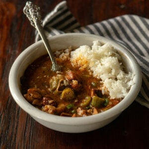 Chicken and sausage gumbo served in a white bowl with a vintage spoon.
