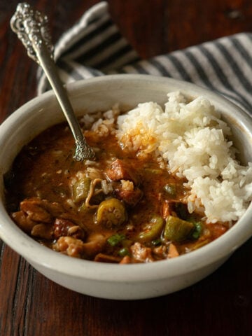 Chicken and sausage gumbo served in a white bowl with a vintage spoon.