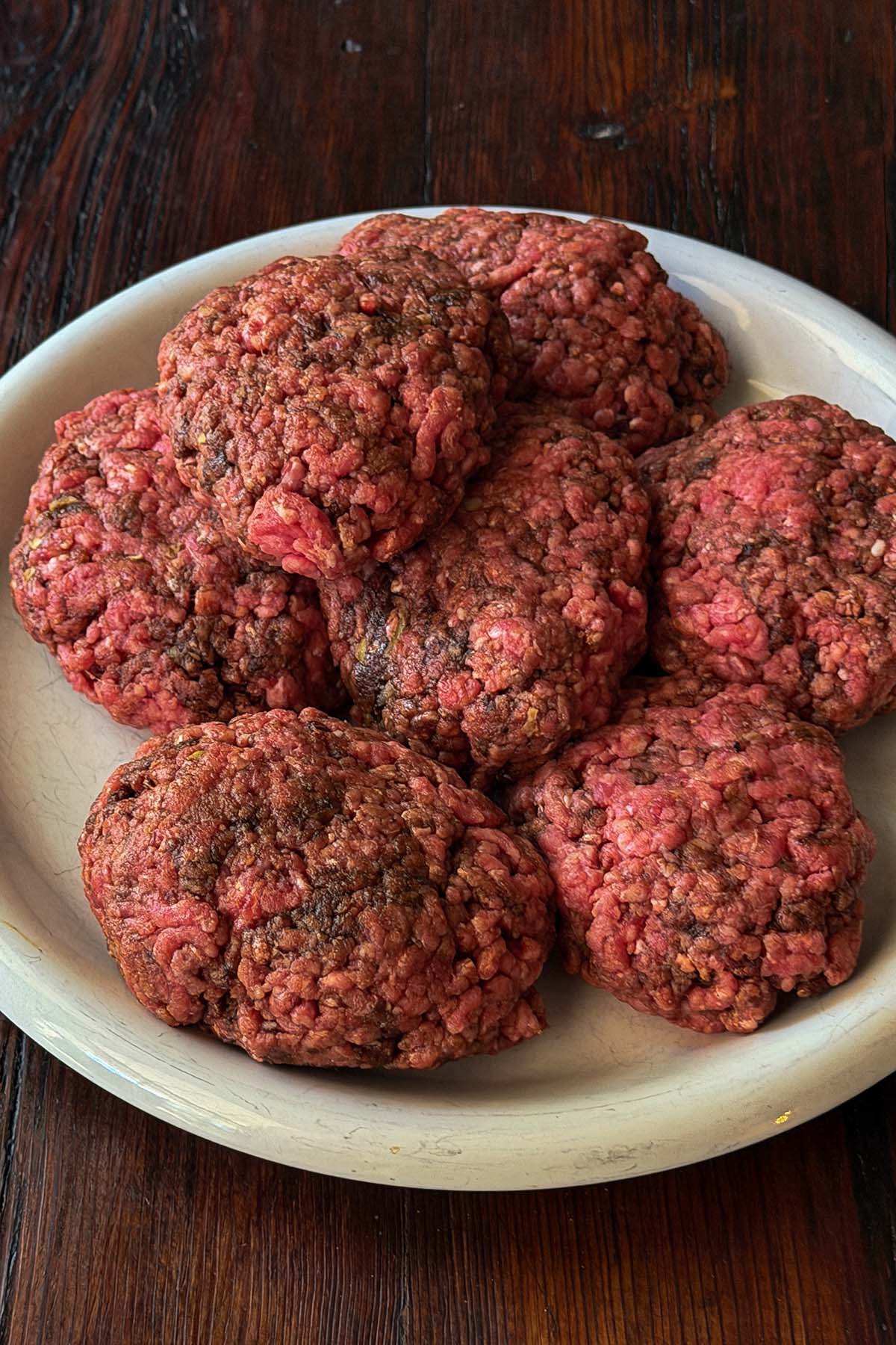 Hamburger steaks formed and piled on a plate.