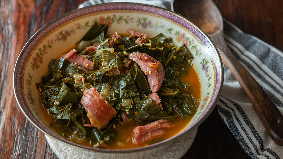 Collard greens served in a vintage decorative bowl on a wooden table.