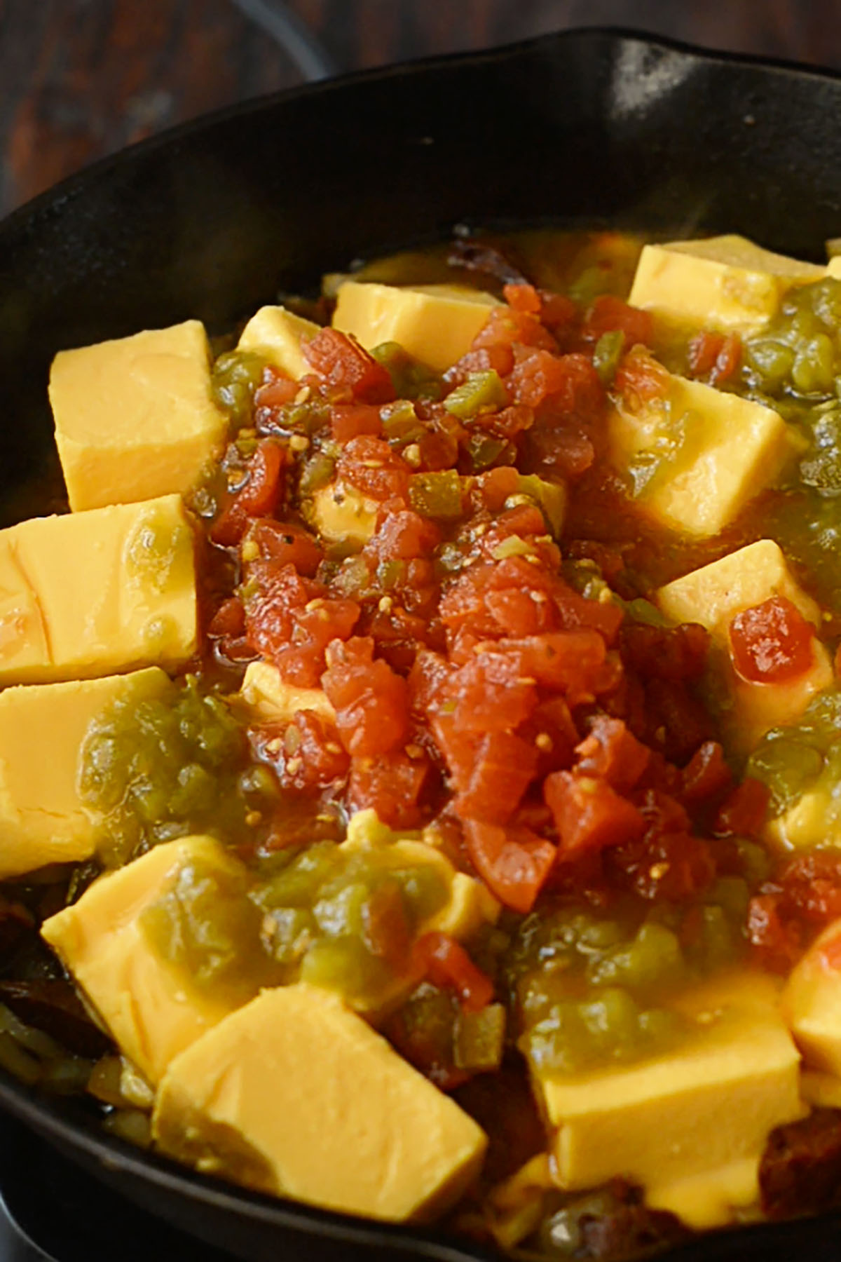 Cubed Velveeta Cheese in a cast iron skillet with rotel and diced green chiles.