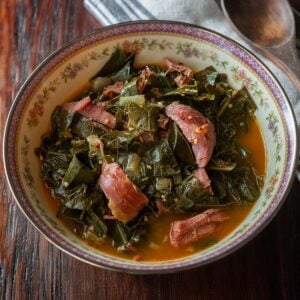 Collard greens with chunks of smoked turkey legs served in a vintage decorative bowl.